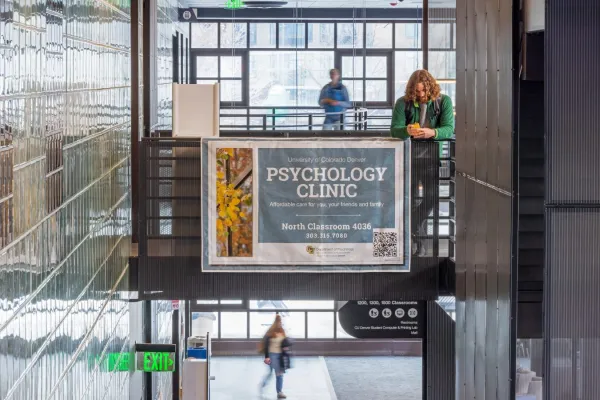 A light-filled interior of a CU Denver building with a banner advertising the CU Denver Psychology Clinic