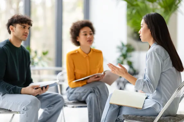 A diverse group of young professionals sit on chairs in a semicircle and have an animated discussion