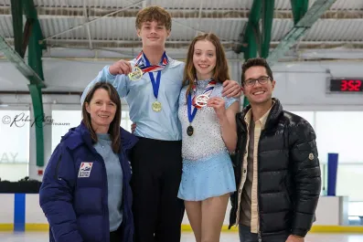 Hudson Lewis poses with teammate and coaches while holding up a medal.