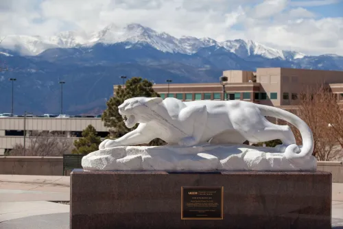 A mountain lion statue in front of the rocky mountains